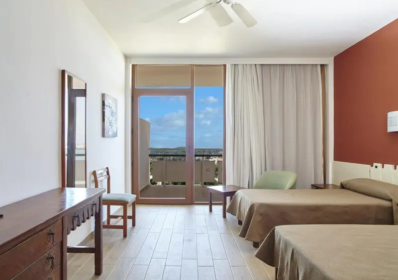 Chambre lumineuse avec deux lits simples et vue sur l'extérieur.