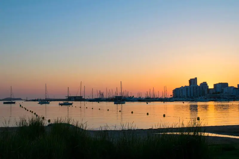 Coucher de soleil sur un port de plaisance avec des bateaux amarrés.
