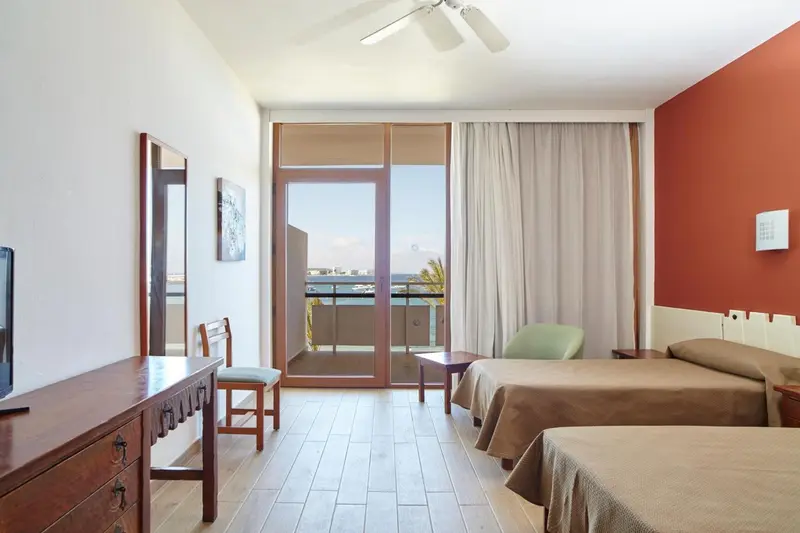 Une chambre lumineuse avec deux lits et un accès à un balcon.