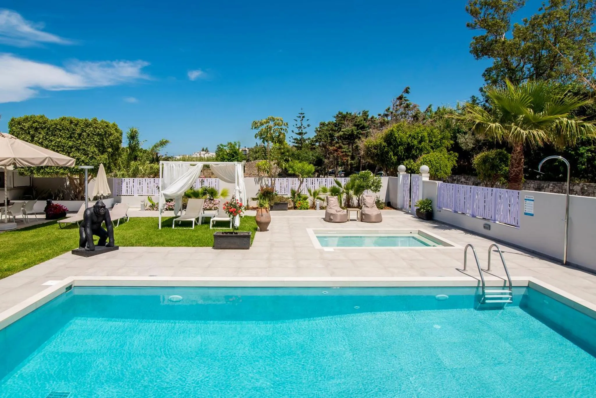 Une piscine turquoise bordée d'une terrasse ensoleillée avec des transats et des palmiers.