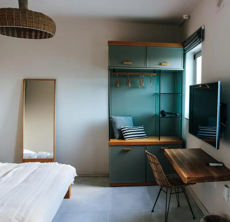 Une chambre lumineuse avec un bureau en bois et un grand miroir.
