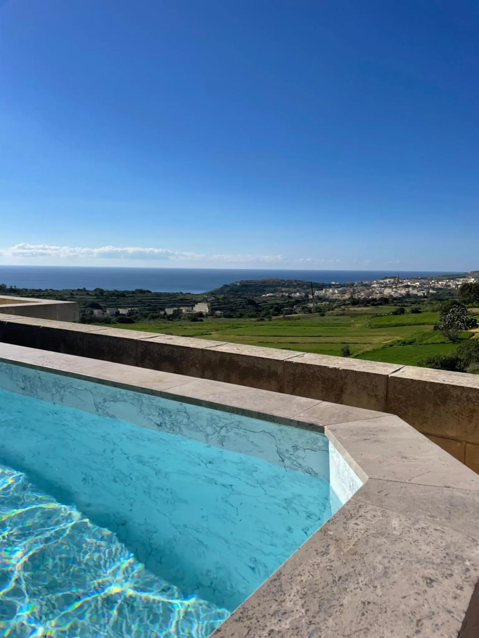 Vue sur la mer et la campagne depuis le bord d'une piscine.