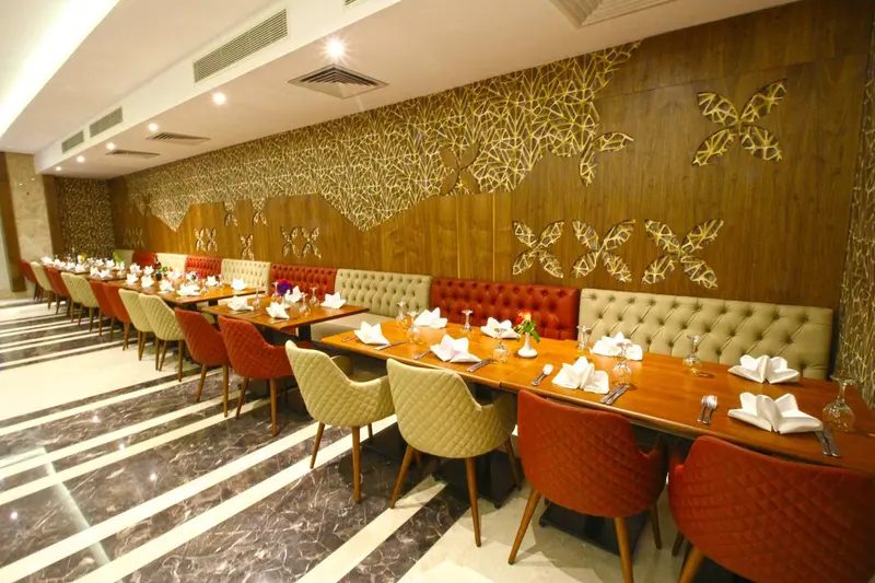 Une salle de restaurant lumineuse avec des tables dressées et des banquettes confortables.