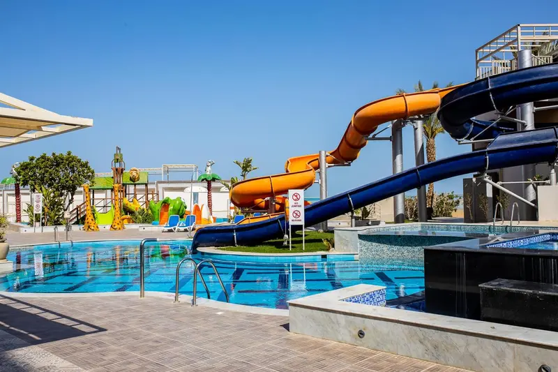 Toboggans aquatiques colorés se terminant dans une piscine ensoleillée.