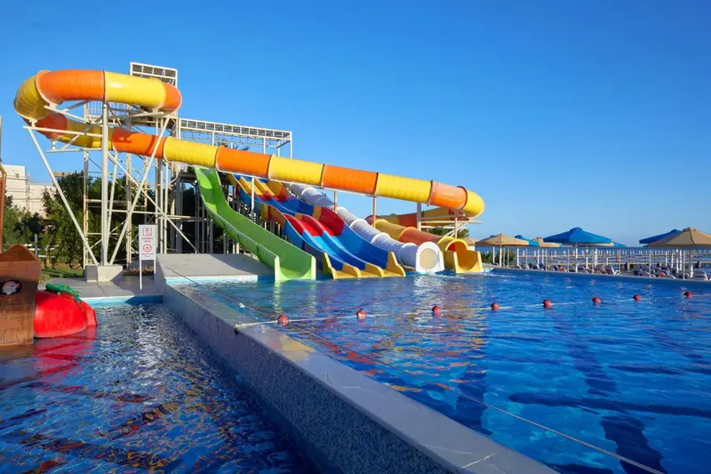 Toboggans aquatiques colorés surplombant une piscine ensoleillée.