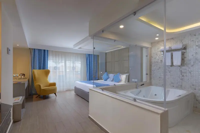 Une chambre lumineuse avec un grand lit et une baignoire jacuzzi.