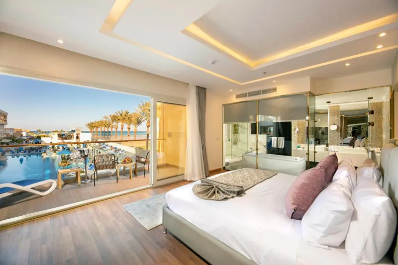 Chambre lumineuse avec un grand lit et une vue sur la mer.