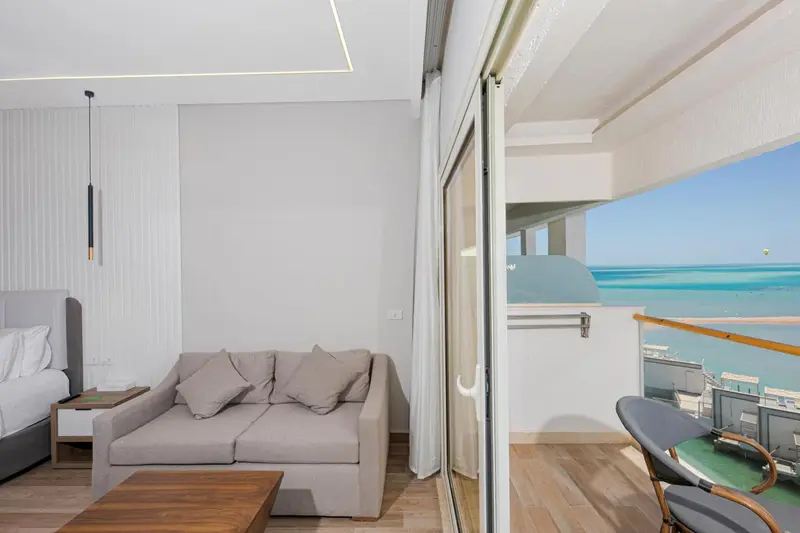 Espace de vie lumineux avec canapé et accès à un balcon offrant une vue sur la mer.