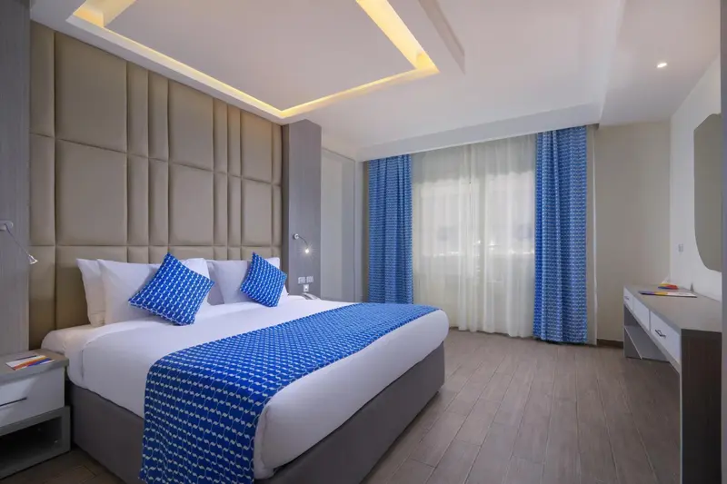 Chambre d'hôtel moderne avec un grand lit et des coussins bleus.