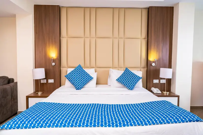 Une chambre lumineuse avec un grand lit recouvert d'une courtepointe à motifs.