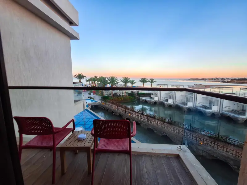 Terrasse avec mobilier rouge donnant sur une piscine et la mer au loin.