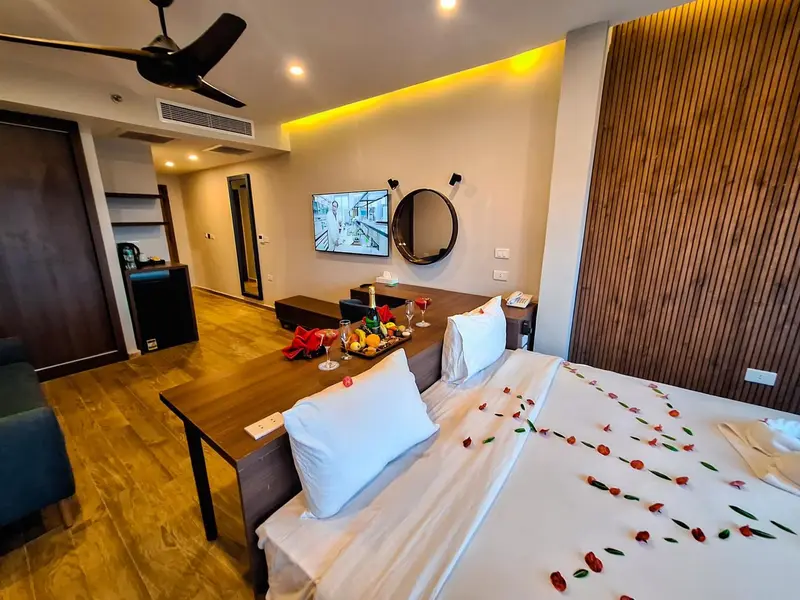 Une chambre décorée avec un lit préparé et une table avec des fruits et des verres.