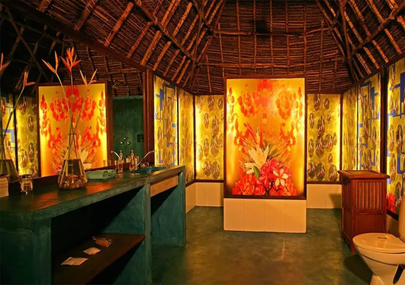 Une salle de bain lumineuse avec des œuvres d'art florales et un comptoir en pierre.