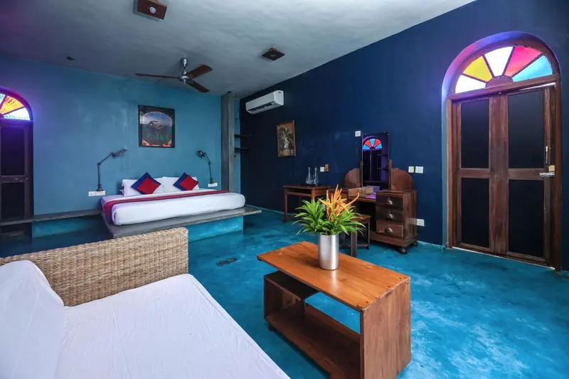 Une chambre lumineuse avec un lit double et un coin salon.