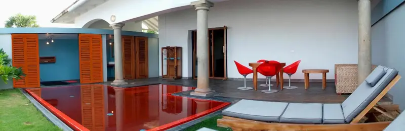 Terrasse avec mobilier de jardin et piscine rouge.
