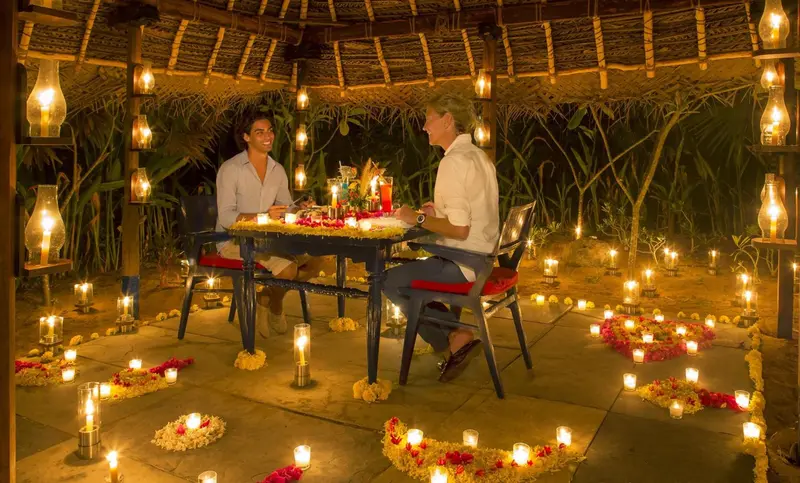 Une table est dressée pour un dîner romantique à la lumière des bougies sur une terrasse.