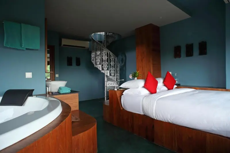 Une chambre spacieuse avec un lit blanc et un bain à remous.