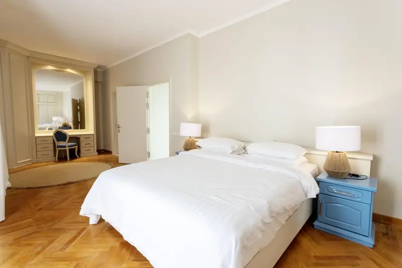 Une chambre lumineuse avec un grand lit et un coin coiffeuse.