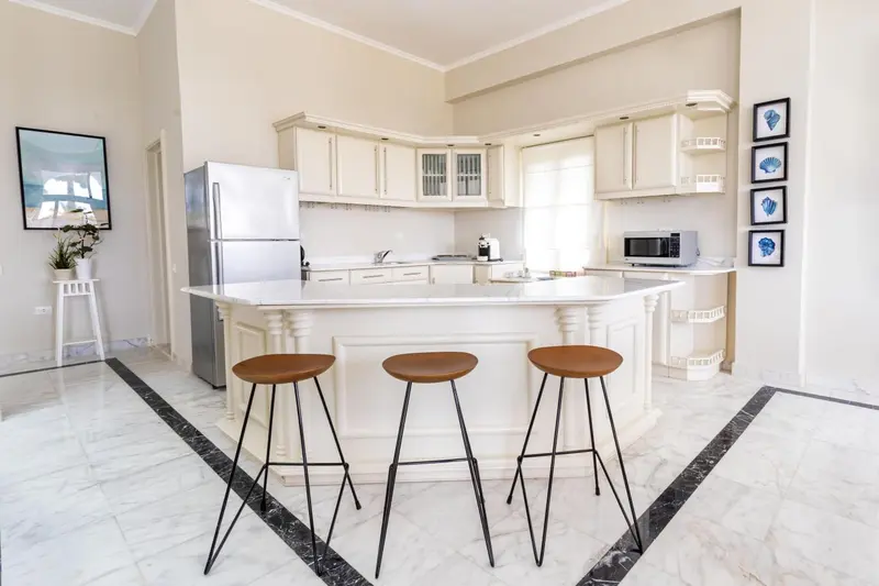 Cuisine lumineuse avec un îlot central et des tabourets.