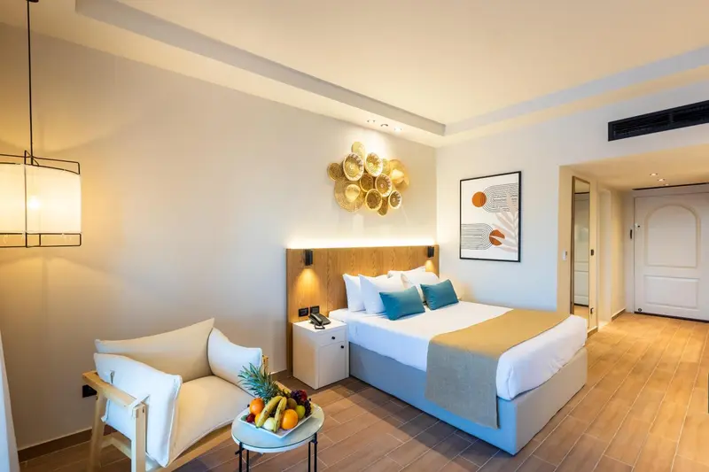 Une chambre lumineuse avec un lit double et un fauteuil.