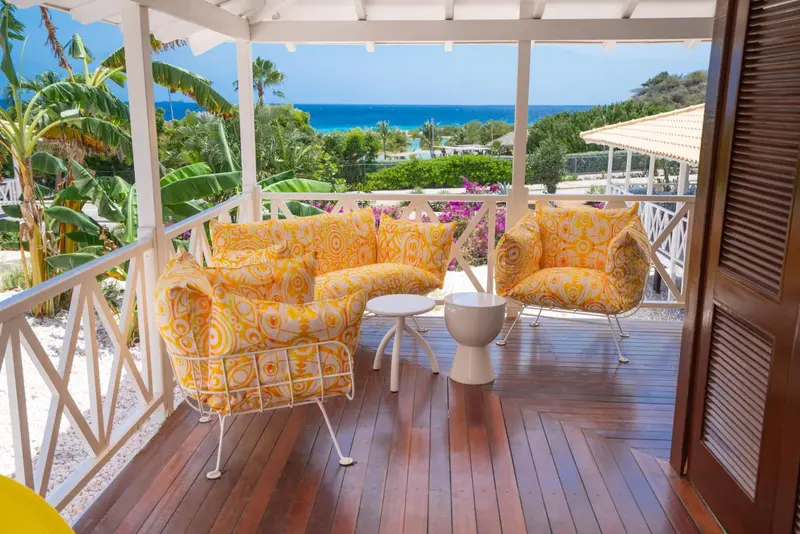 Espace de détente extérieur avec mobilier coloré et vue sur la végétation et la mer.