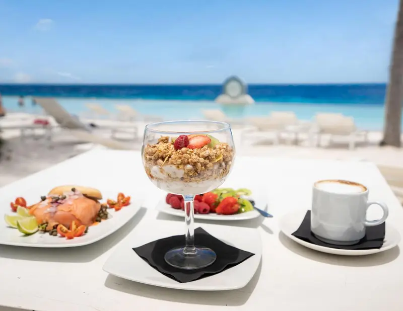 Un petit-déjeuner copieux est servi sur une table blanche en bord de mer.