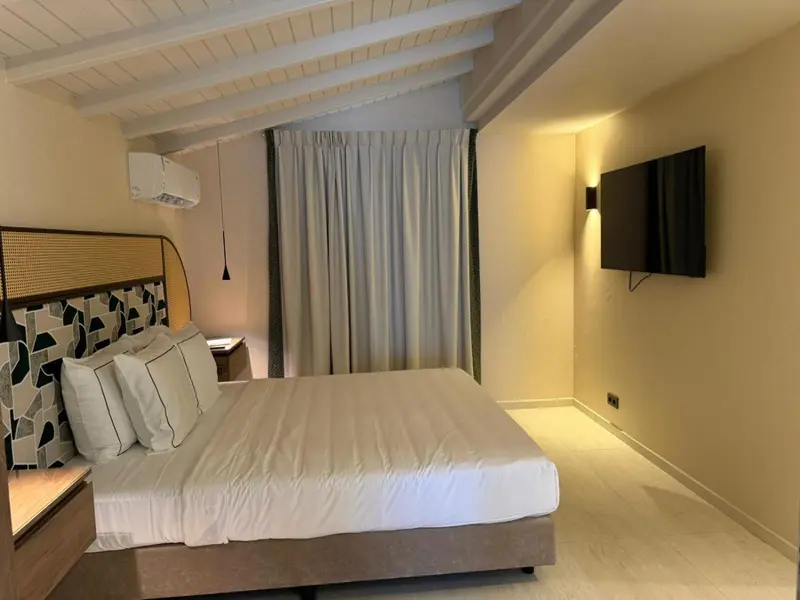 Une chambre lumineuse avec un grand lit et une télévision murale.