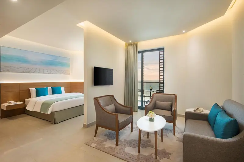 Une chambre lumineuse avec un lit et un coin salon.