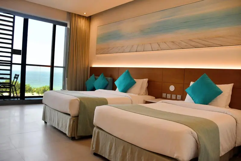 Une chambre lumineuse avec deux lits simples et une vue sur la mer.
