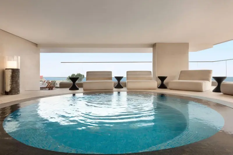 Espace de détente intérieur avec piscine et vue sur la mer.