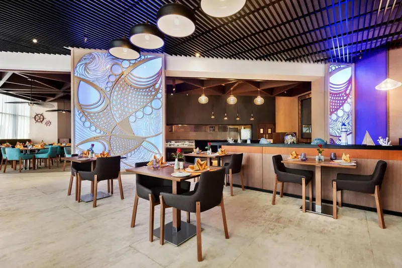 Une salle de restaurant lumineuse avec des tables dressées et une décoration moderne.