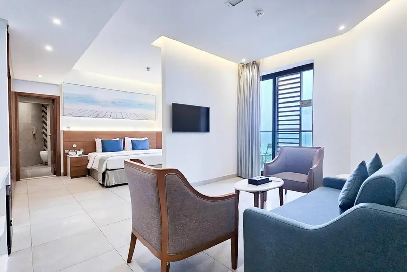 Une chambre lumineuse avec un coin salon et un accès à un balcon.