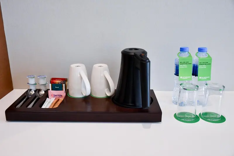 Une bouilloire électrique et des tasses sur un plateau en bois.