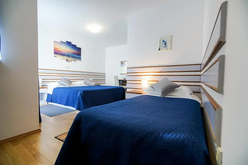 Chambre lumineuse avec deux lits simples et décoration murale.