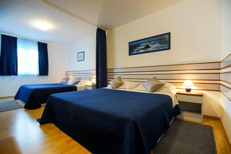 Une chambre lumineuse avec deux lits et une décoration sobre.