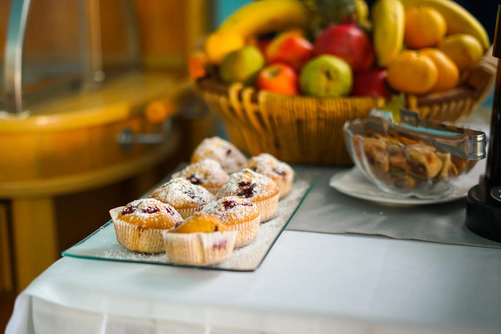Une table présente des pâtisseries et un panier de fruits frais.