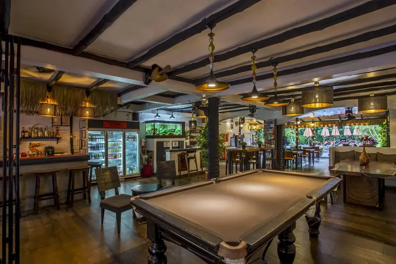 Une salle lumineuse avec un bar, des tables et un billard.