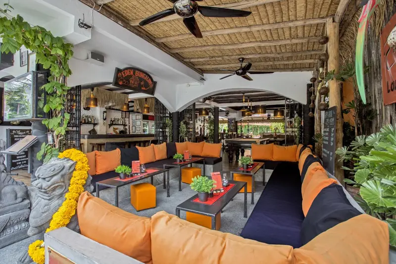 Un espace de détente extérieur avec des canapés orange et des tables basses.