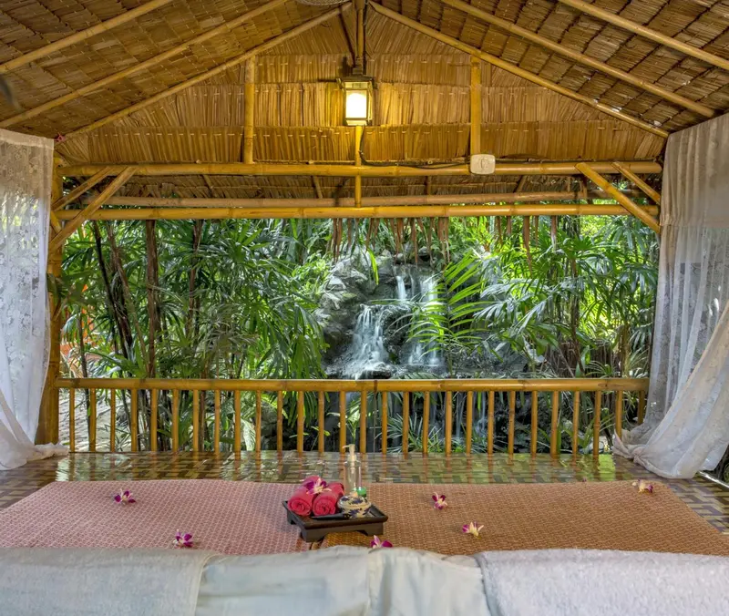 Espace de détente extérieur avec un lit et une cascade en arrière-plan.