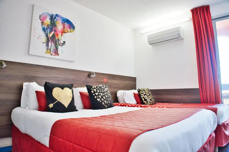Une chambre avec un lit double et une décoration murale colorée.
