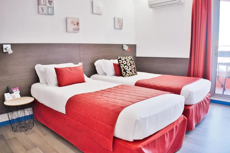 Une chambre avec deux lits simples et une décoration rouge et blanche.
