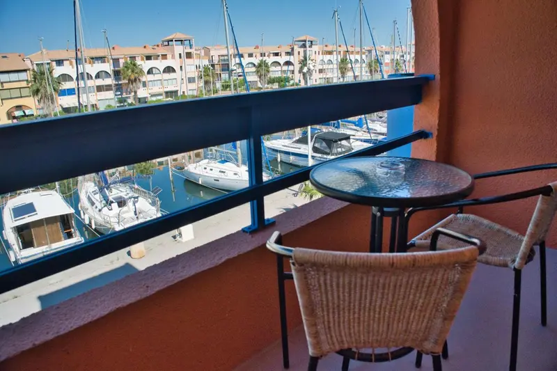 Terrasse avec mobilier donnant sur un port de plaisance ensoleillé.