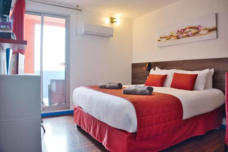 Une chambre lumineuse avec un grand lit et un accès à une terrasse.