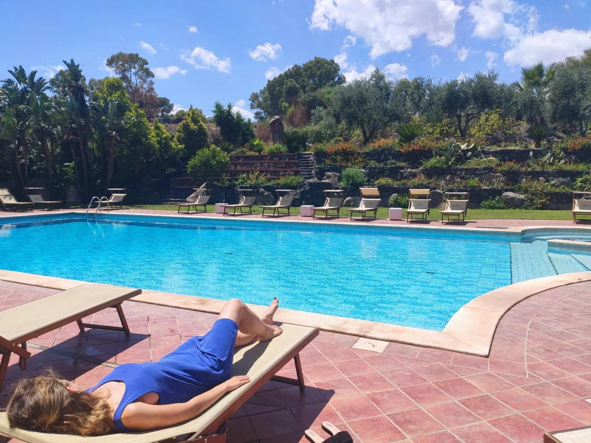 Une personne se relaxe au bord d'une piscine ensoleillée.