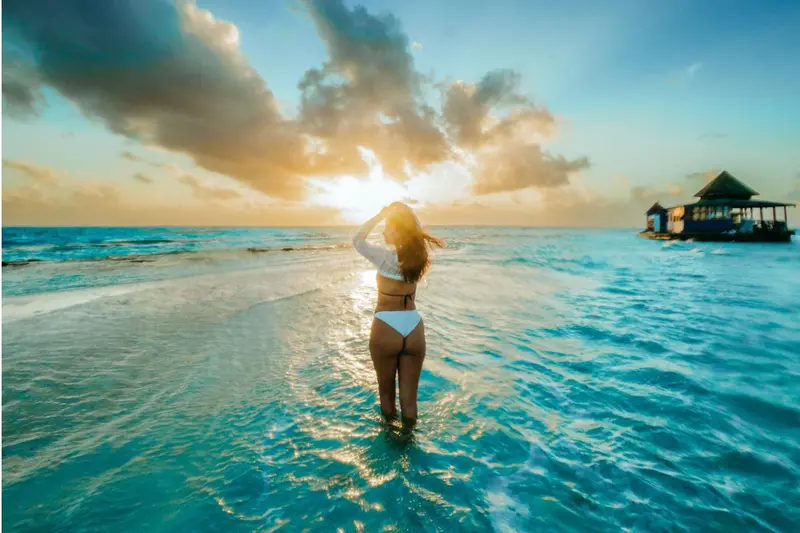 Une personne se tient dans l'eau au coucher du soleil.