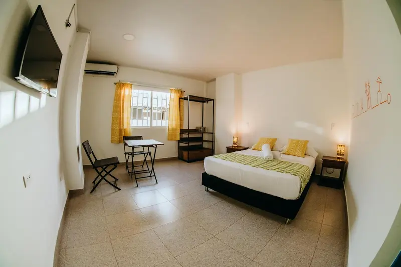 Une chambre lumineuse avec un lit, une table et une chaise.