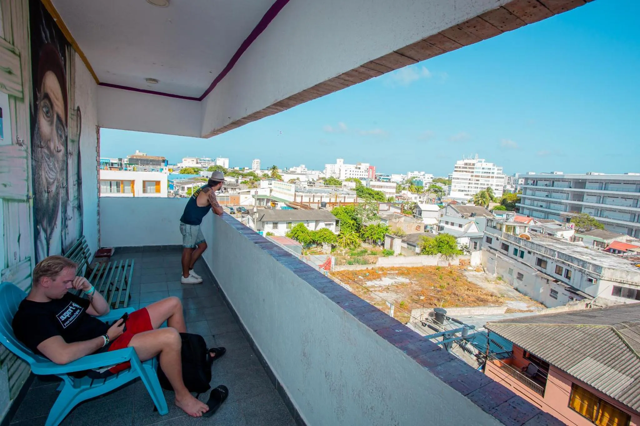 Deux hommes se détendent sur une terrasse avec vue sur la ville et la mer.