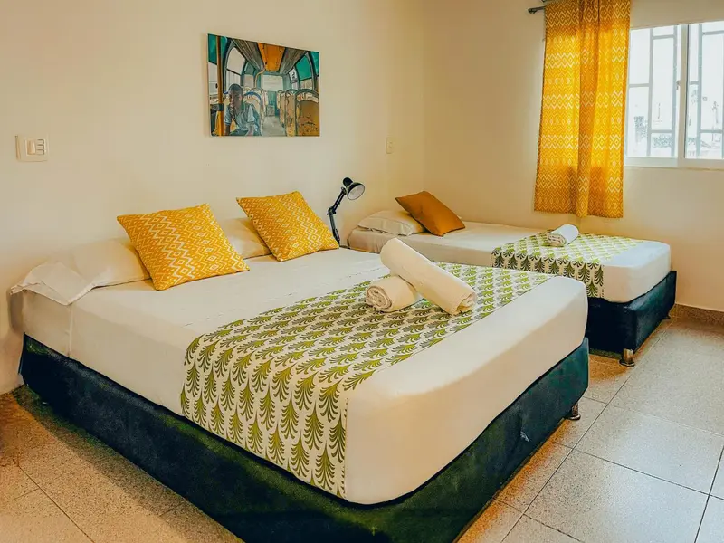 Une chambre lumineuse avec deux lits décorés de coussins.