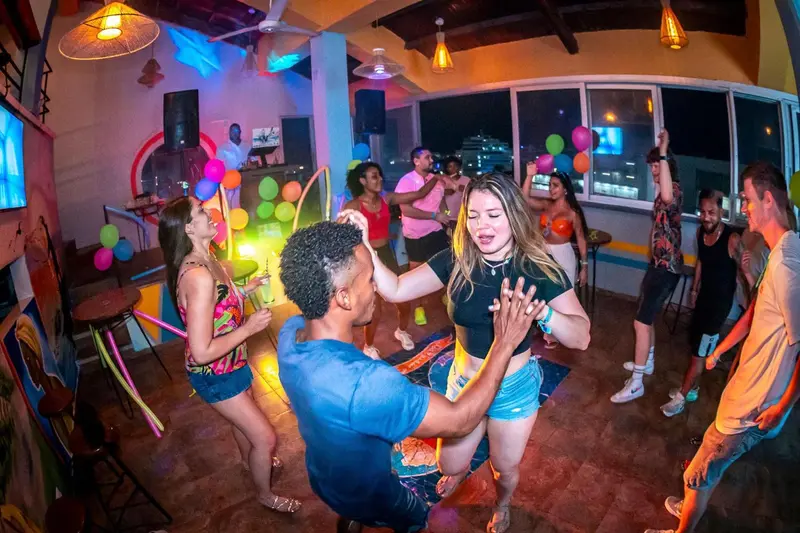 Une foule danse dans une salle illuminée aux couleurs vives.