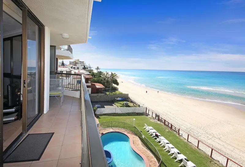 Vue d'un balcon donnant sur une plage et une piscine.